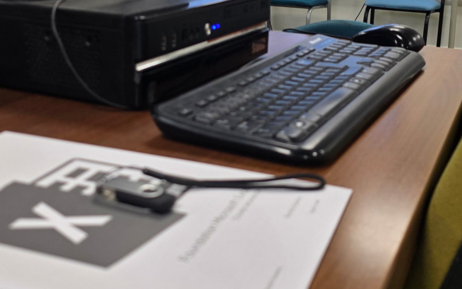A course workbook and a memory stick beside a keyboard in a training room