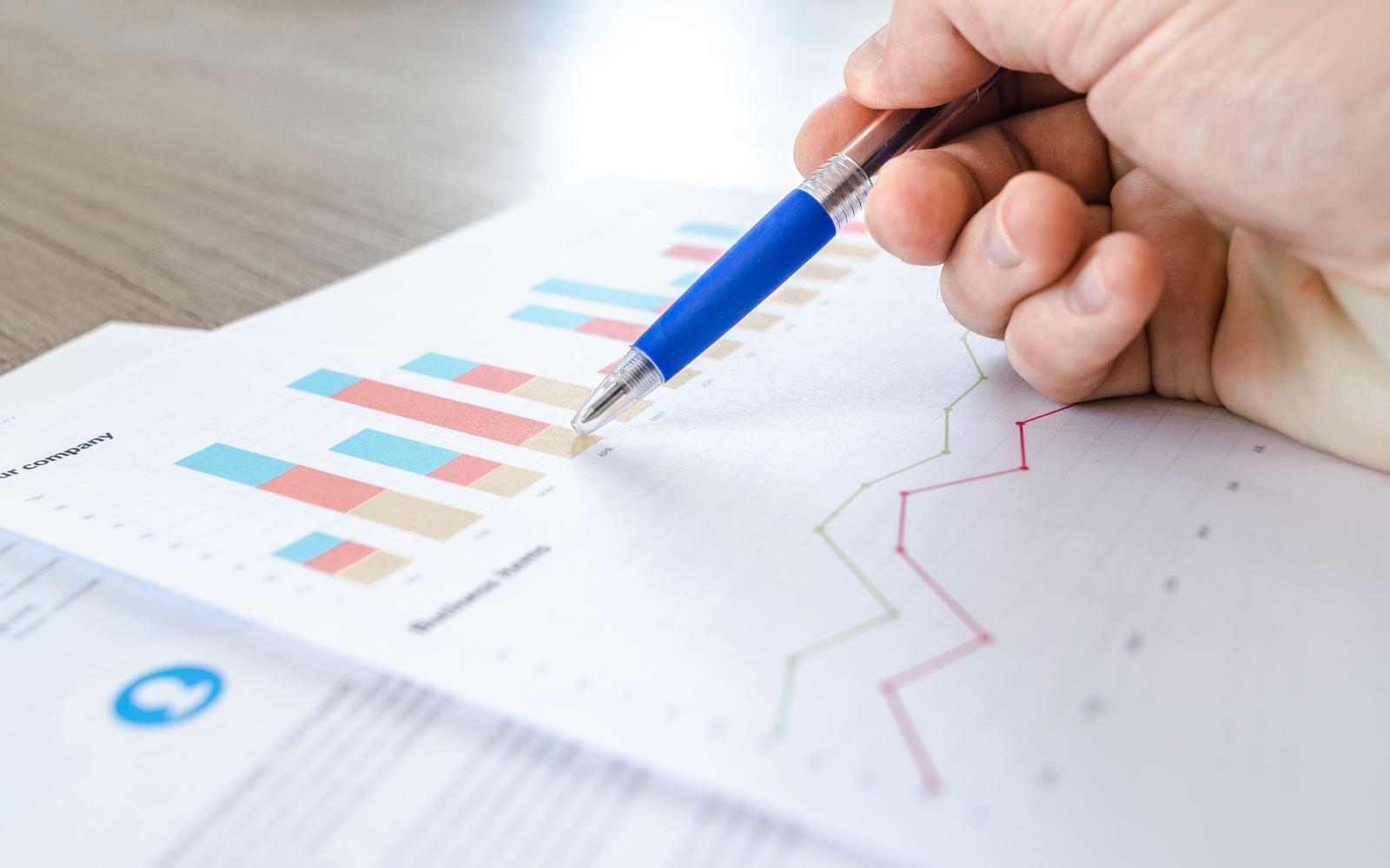 A hand pointing a pen at a printed bar chart